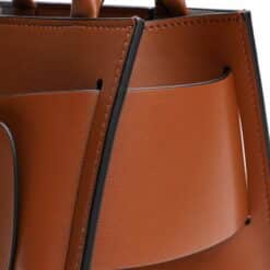 Brown leather handbag featuring black accents and a structured design, ideal for fashion enthusiasts and accessory lovers.